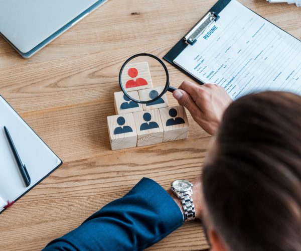 top view of man holding magnifier near wooden cubes